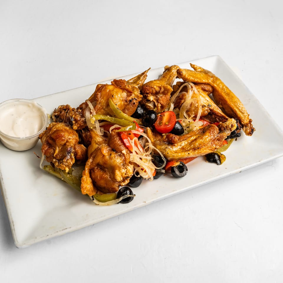 Crispy chicken wings with sautéed onions, peppers, tomatoes, black olives, and a side of dipping sauce.